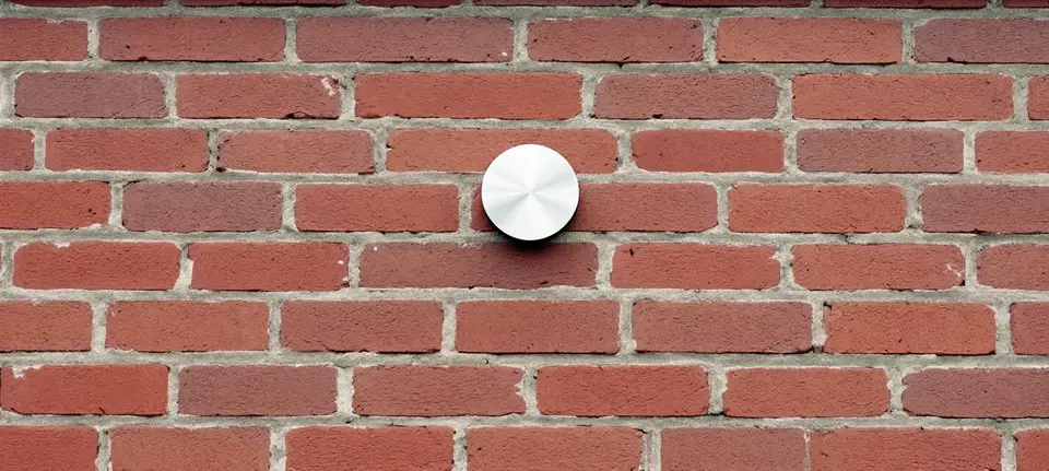 Een rond roestvrijstalen ventilatiekapje in een bakstenen gevel